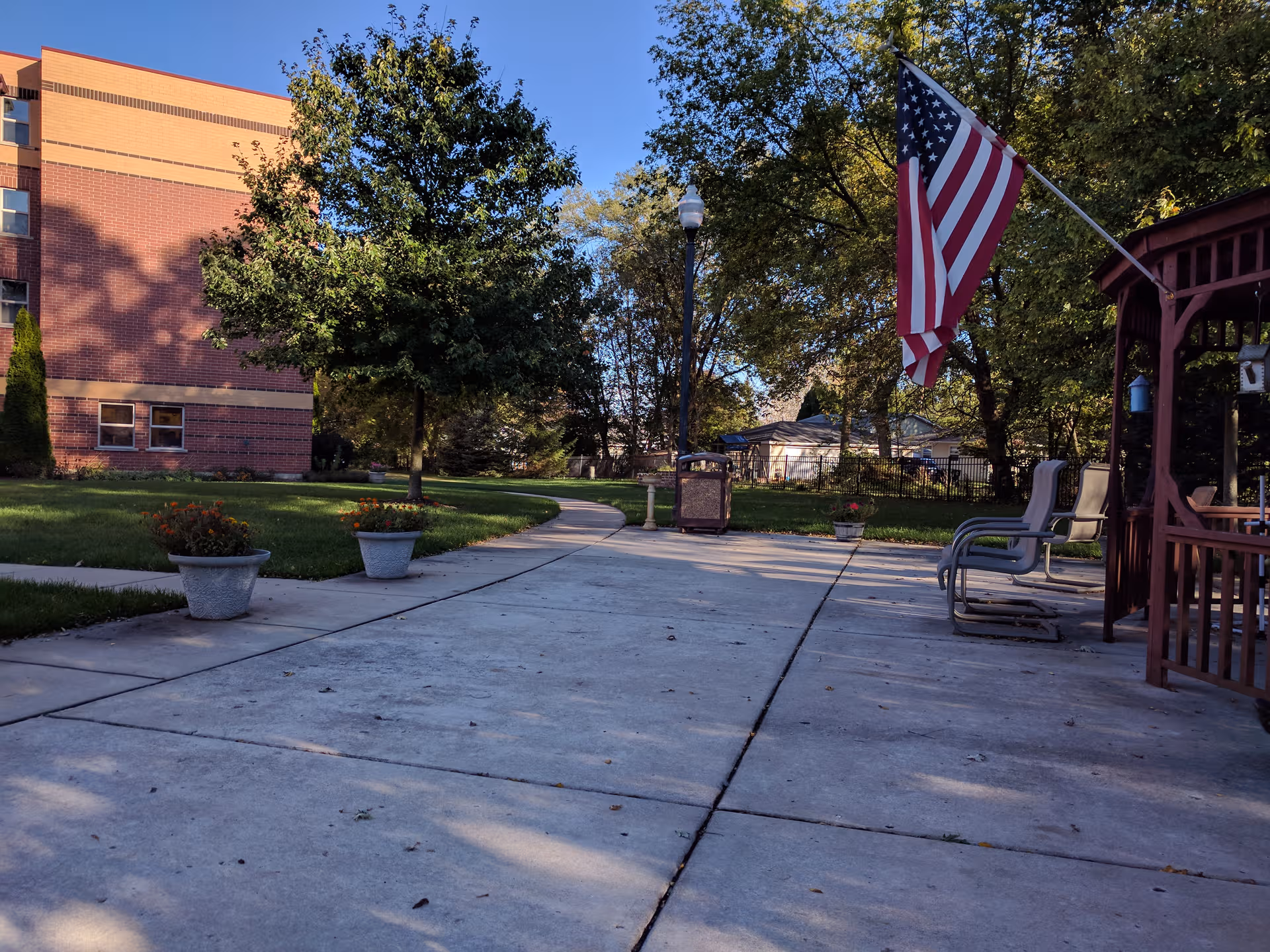Outdoor courtyard of Barton Senior Residences-Zion with flag, potted plants, and seating.
