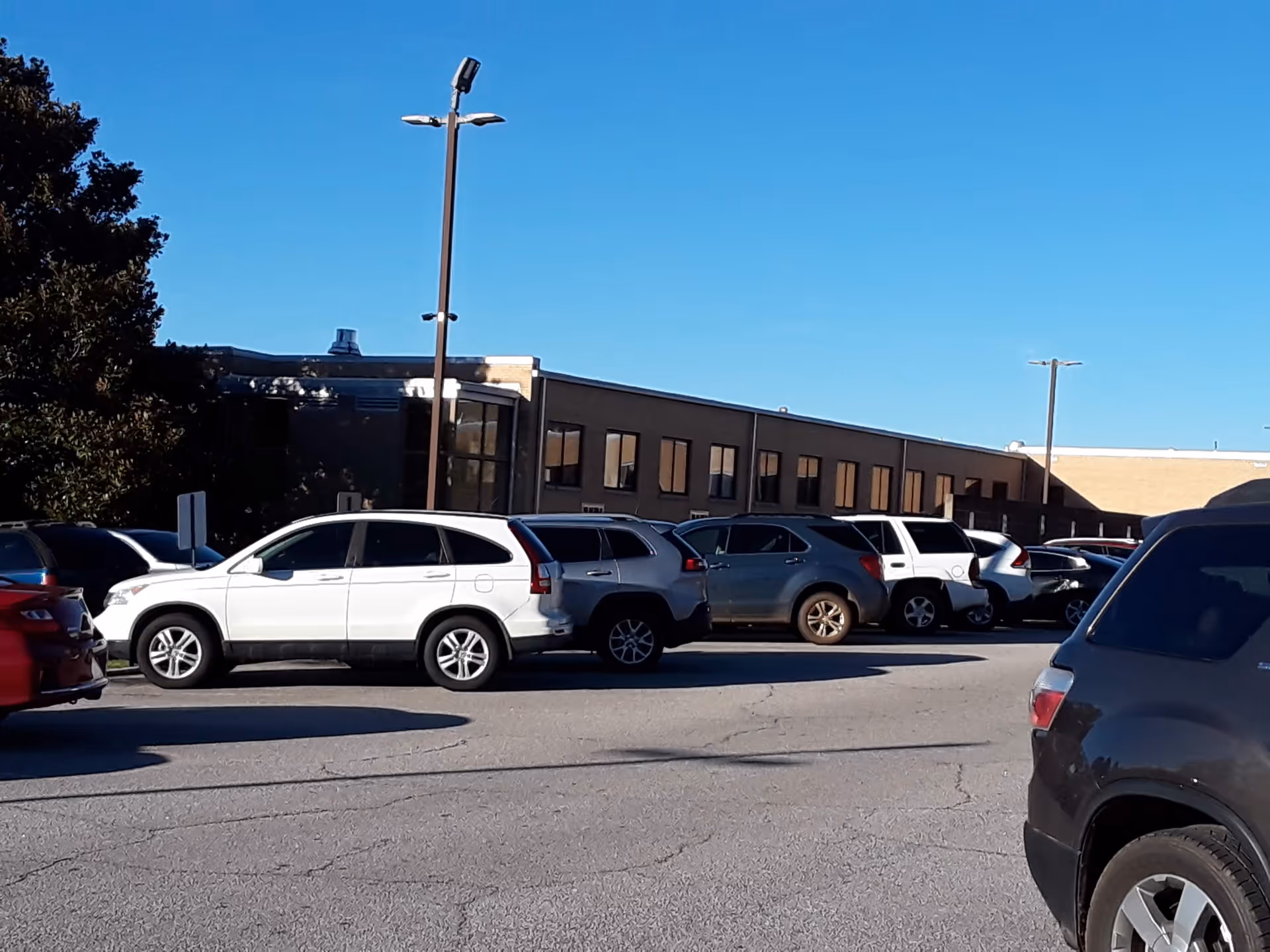 Parking lot with multiple cars in front of a low brick building.
