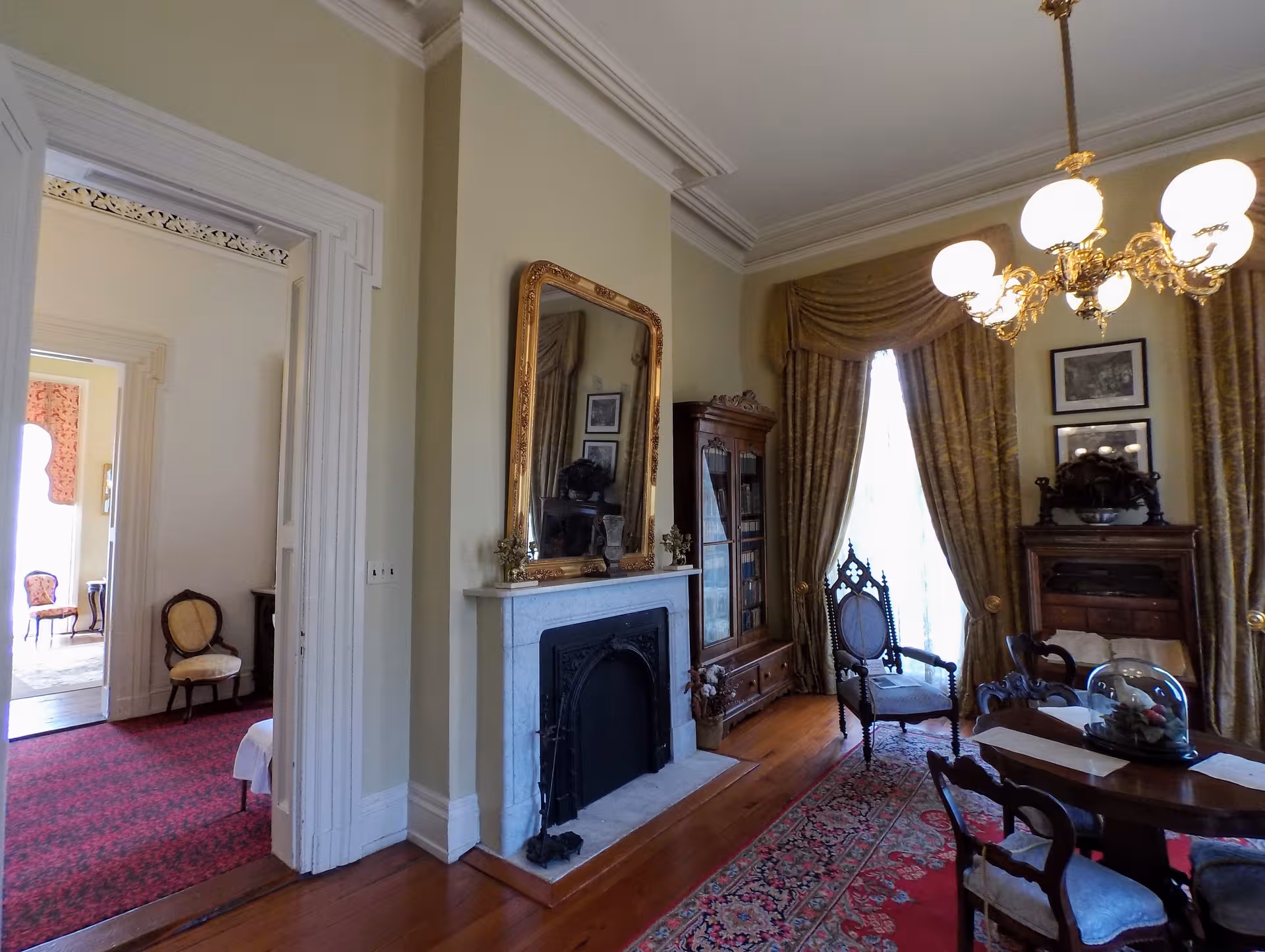 Elegant vintage living room with fireplace, mirror, ornate furniture, and heavy gold curtains.