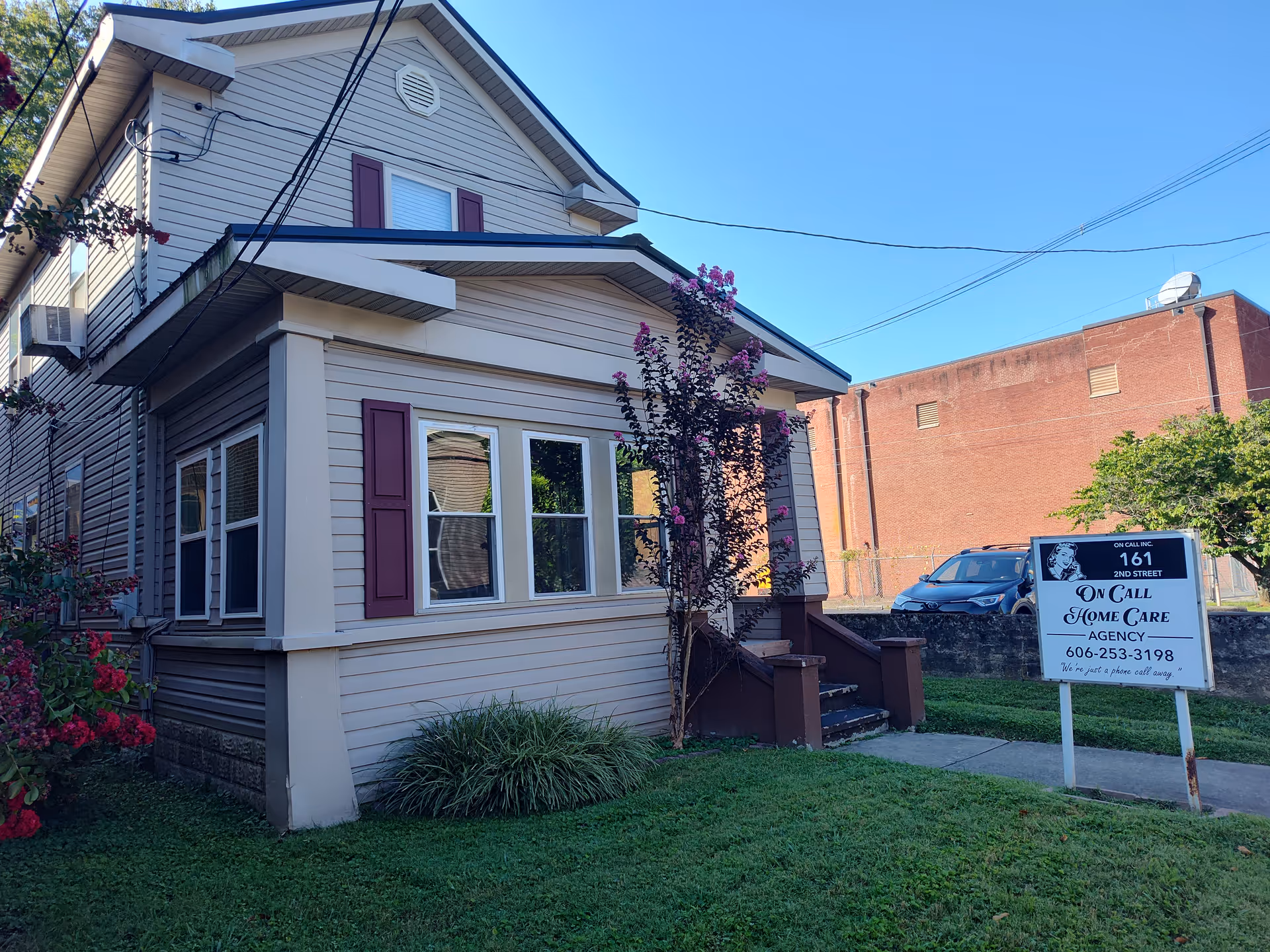 Residential building at the front with steps and a sign advertising home care services.