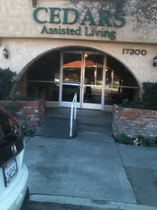 The Cedars Assisted Living entrance with arched glass doors and a wheelchair ramp.