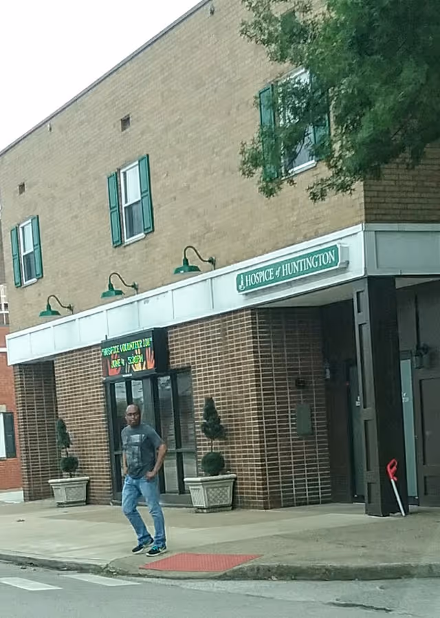 Exterior of Hospice of Huntington building with green signage and a man standing at the entrance.