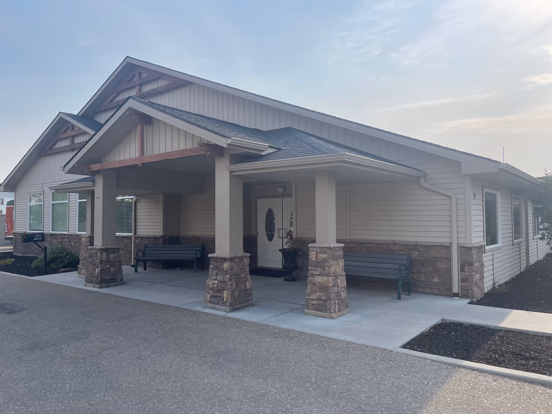 Copper Springs Senior Living exterior showing a covered entrance with stone columns and benches.