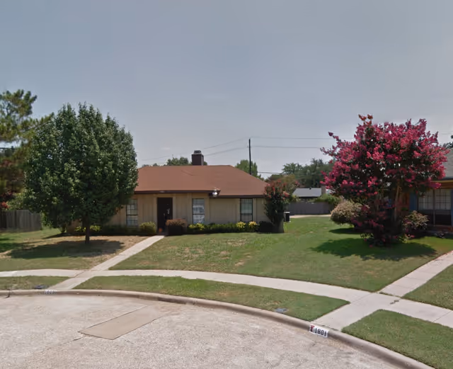One-story residential building with a lawn, trees, and a sidewalk in front