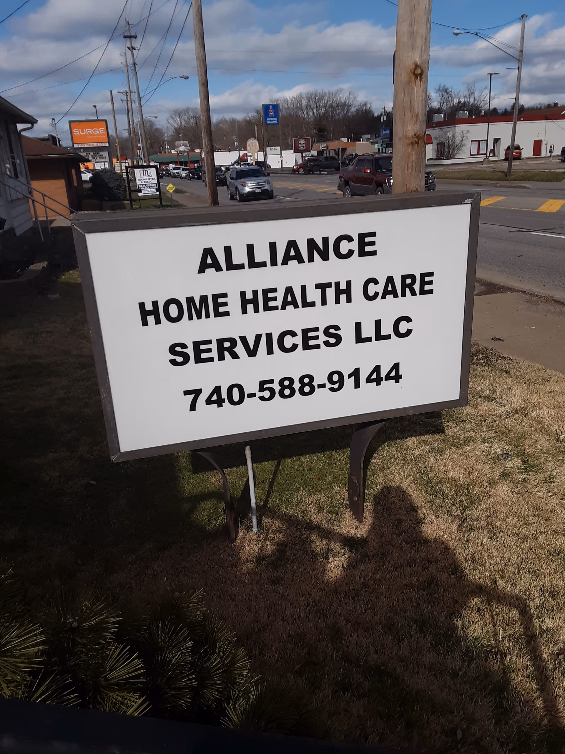 Outdoor street scene featuring a large Alliance Home Health Care Services sign.