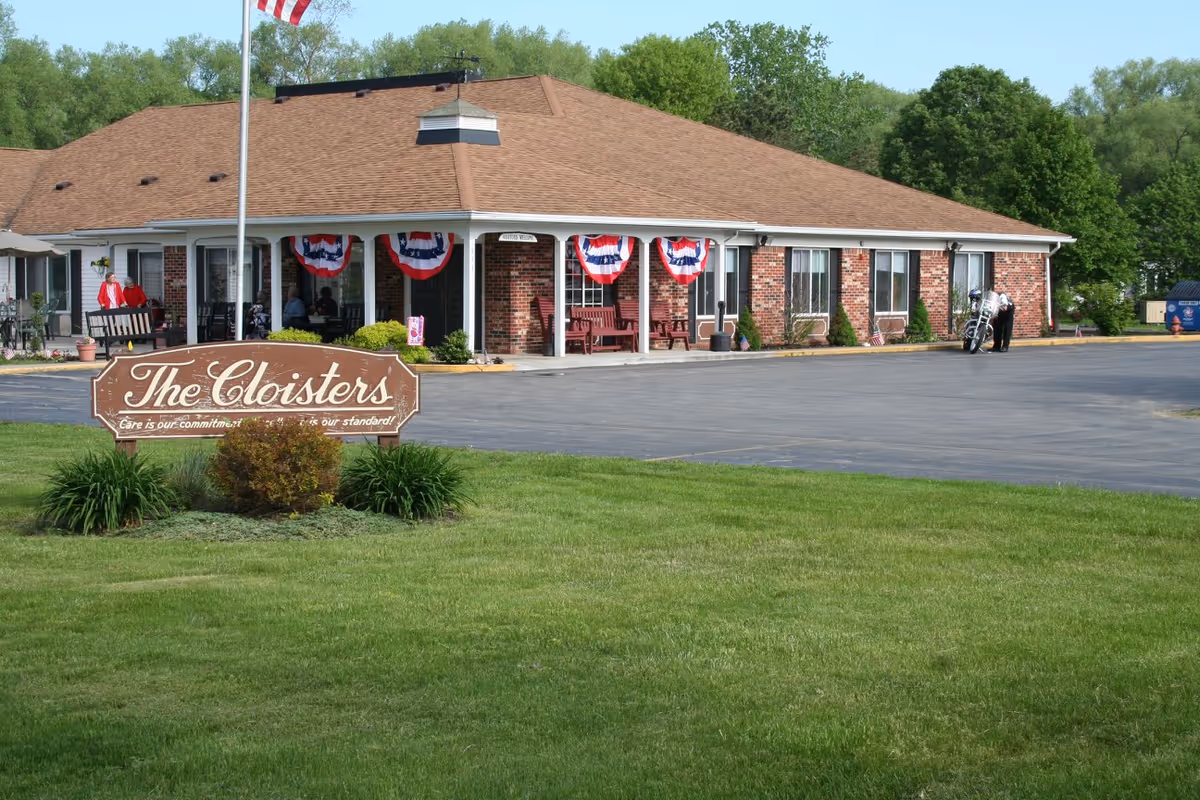 Front view of The Cloisters senior living facility with patriotic bunting and landscaping.