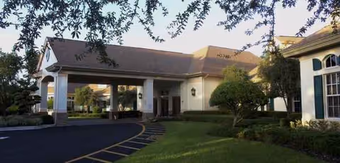 Exterior view of Wellington at Seven Hills entrance with a covered drop-off and landscaped grounds.