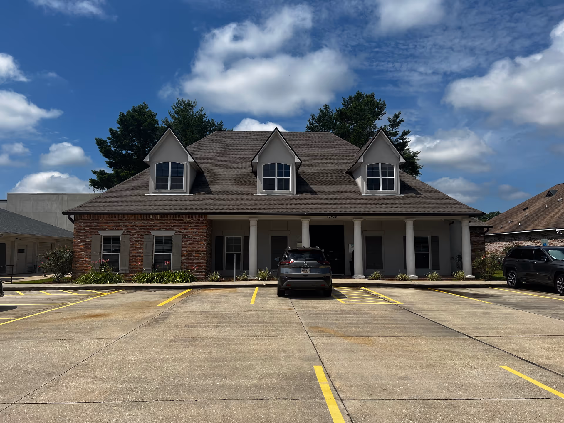 Exterior view of a brick senior care facility with a front entrance and parking.
