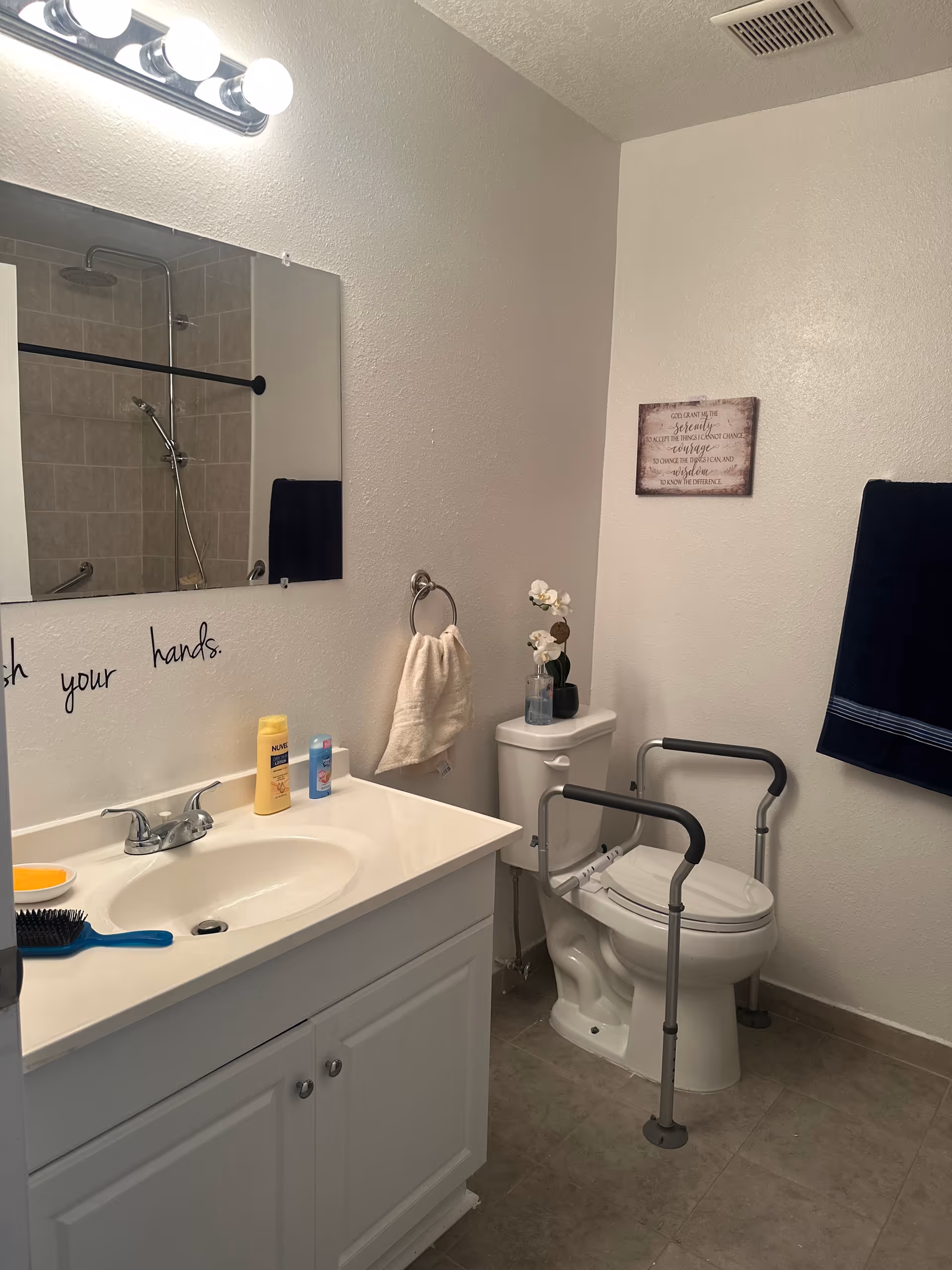 Accessible bathroom with sink, mirror, toilet, grab bars, shower, towels, and toiletries.