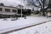 Exterior view of Hughes Health and Rehabilitation, snow-covered with trees and a recessed entrance.