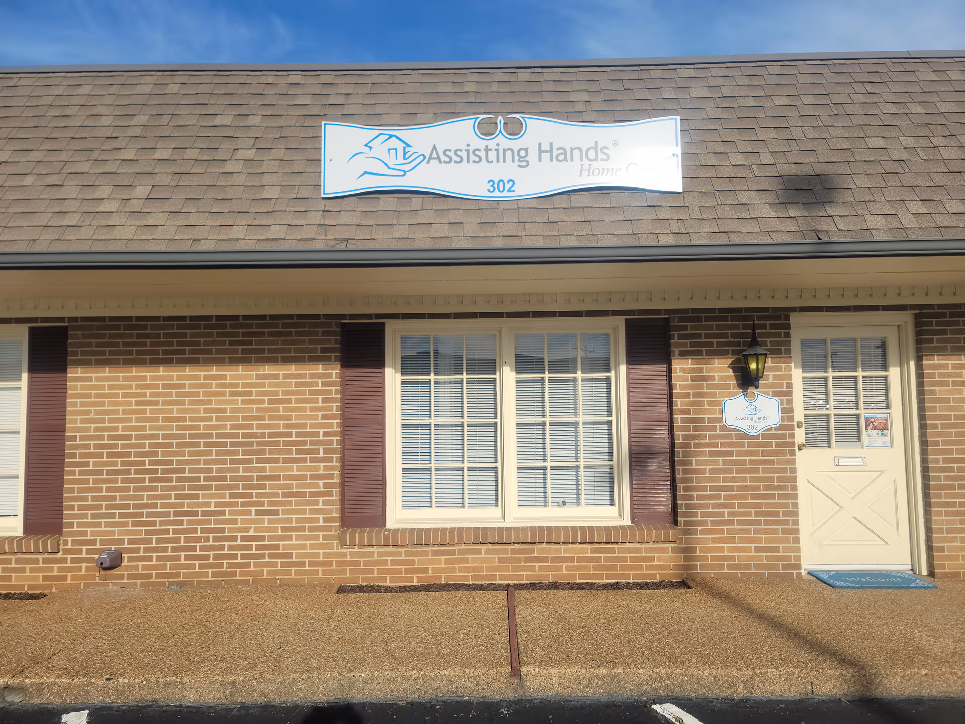 Front exterior of an assisted living facility with a sign that reads Assisting Hands.