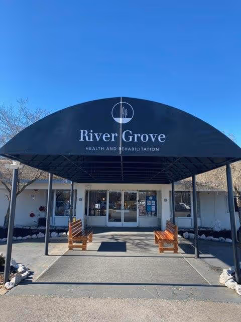 Front entrance of River Grove Health and Rehabilitation with a curved canopy and benches.