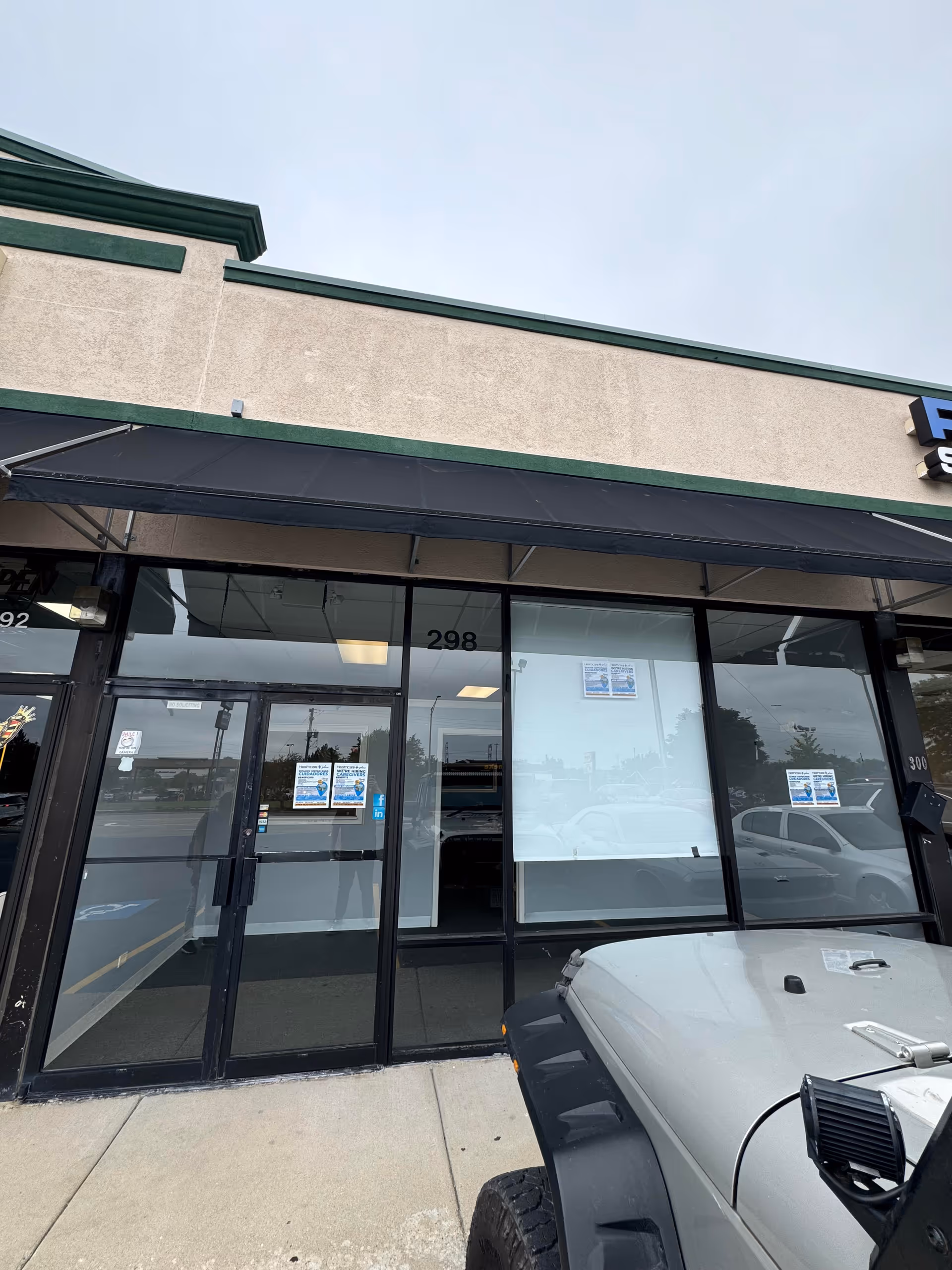 Exterior storefront with glass doors and a parked vehicle in front.