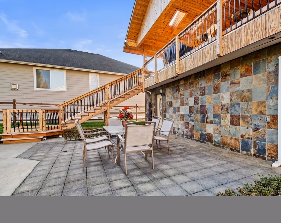 Outdoor patio with table and chairs beside a tiled wall and staircase.