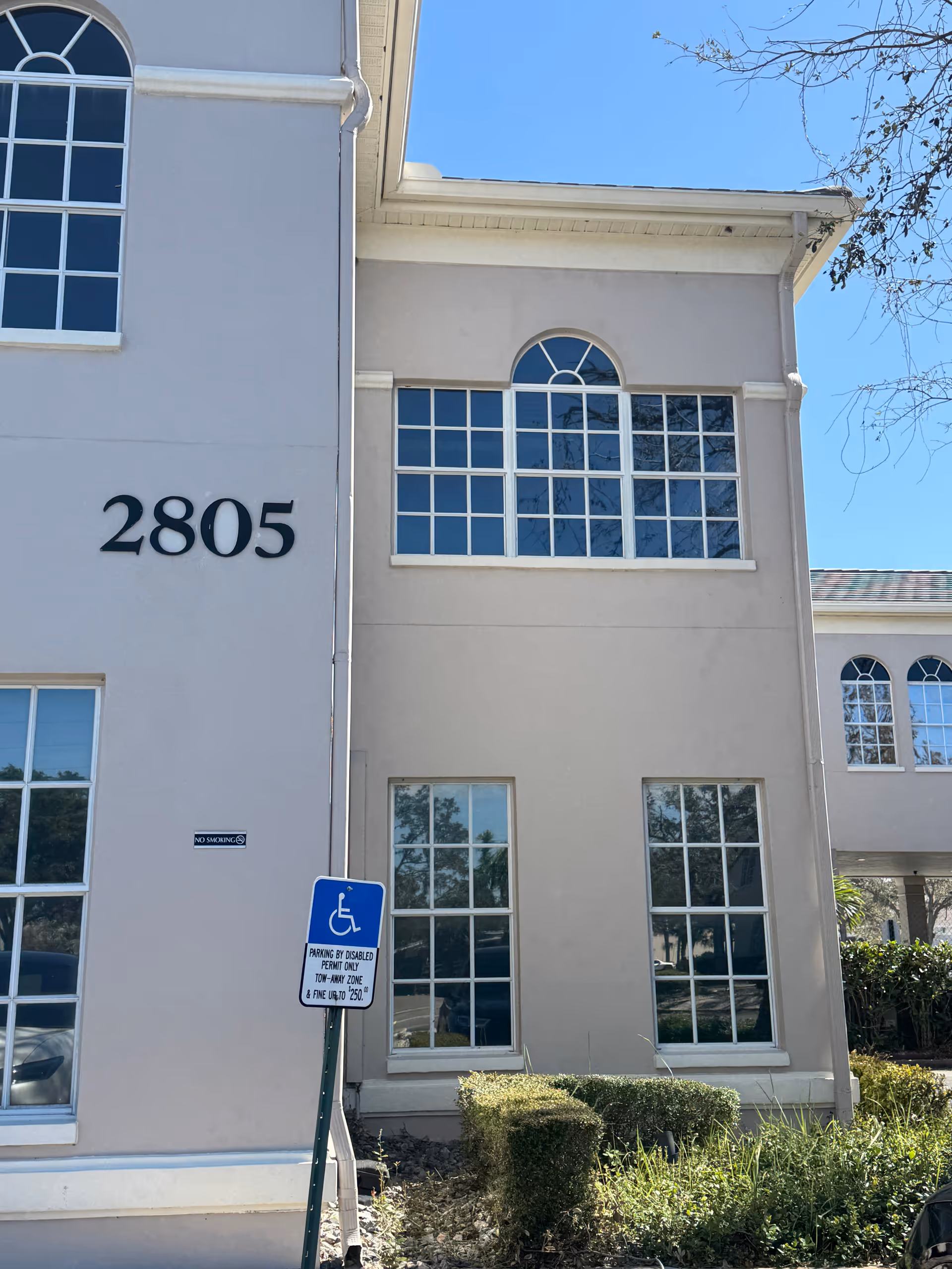 Exterior view of a light-colored building with large arched windows and the number 2805