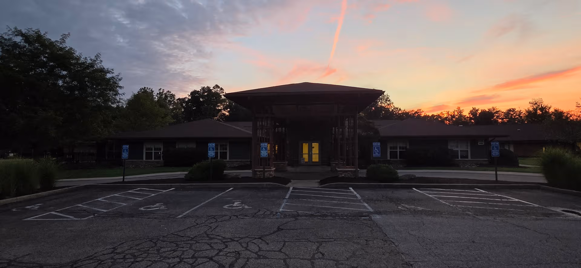 Sunset-lit exterior of Willow Haven Healthcare & Rehabilitation with a covered entrance and parking.