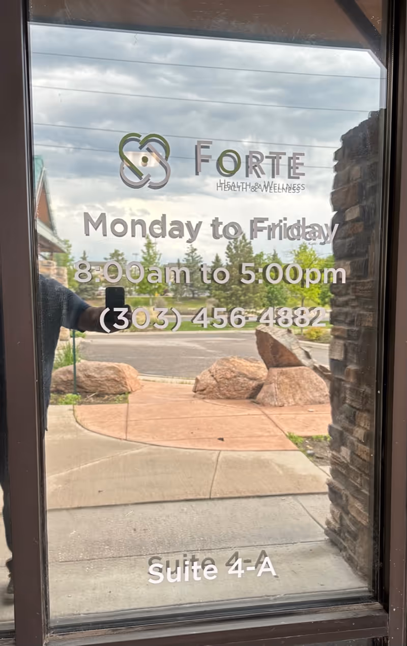 Glass entrance door showing Forte Health and Wellness Wheat Ridge sign and hours.