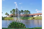 Pond with fountain, landscaped greenery, and red-roofed senior living buildings in the background.
