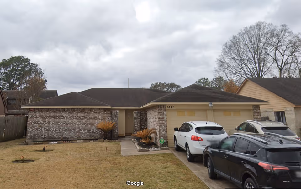 Front exterior of a single-story brick facility with a two-car garage and parked cars.