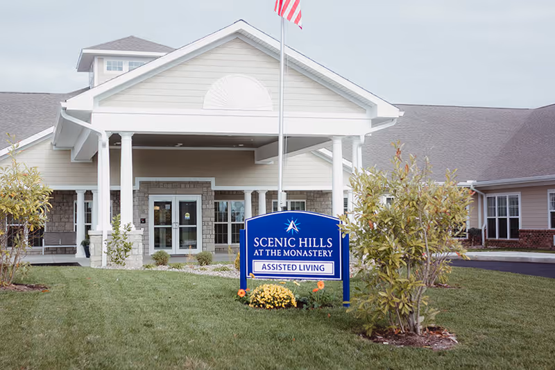 Senior living facility front entrance with blue sign reading Scenic Hills at the Monastery, Assisted Living.