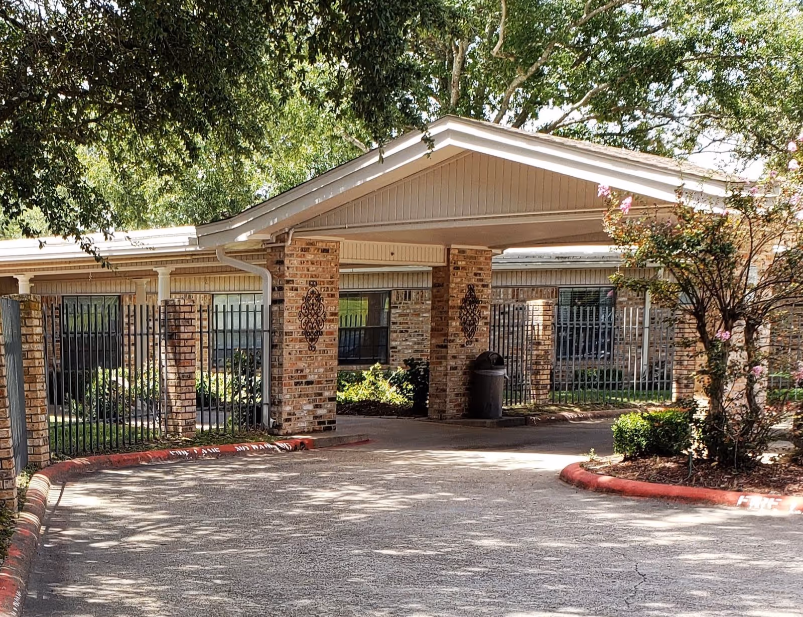 Brick entrance of Pleasant Springs Healthcare Center with a covered drive, columns, and iron fencing.