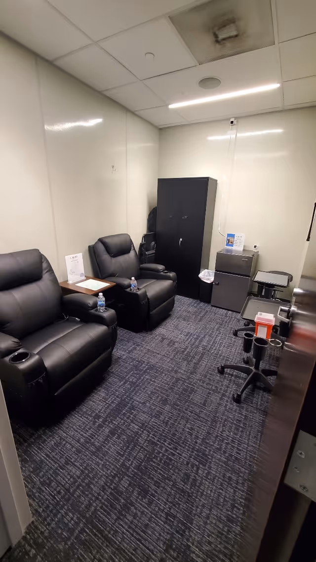 Interior lounge in a care facility with black leather recliners and a cabinet.