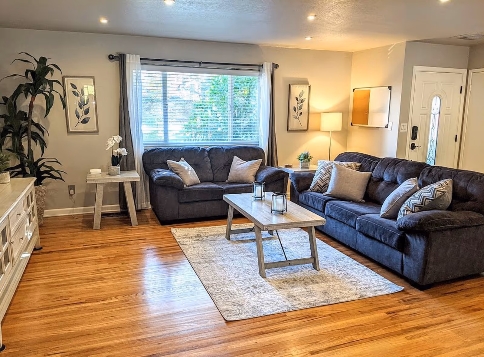 Cozy living room featuring two dark sofas, a coffee table, and neutral decor.
