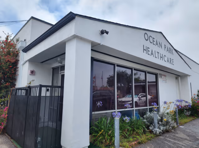 Exterior view of a white healthcare facility with large glass windows and landscaping, Ocean Park Healthcare.