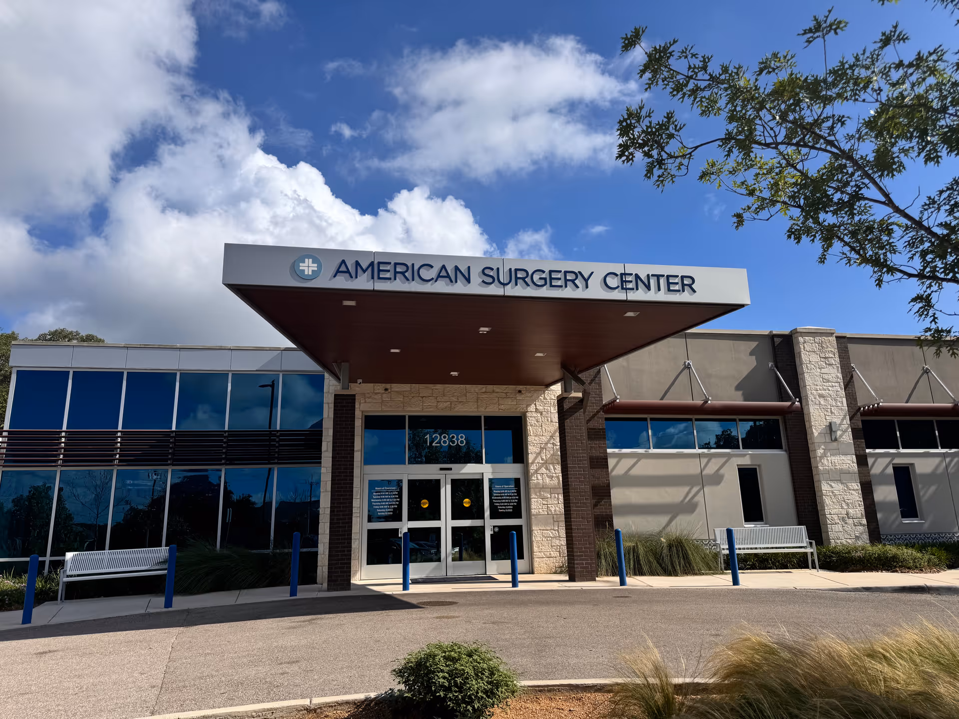 Exterior view of American Surgery Center entrance with glass walls and a covered canopy.
