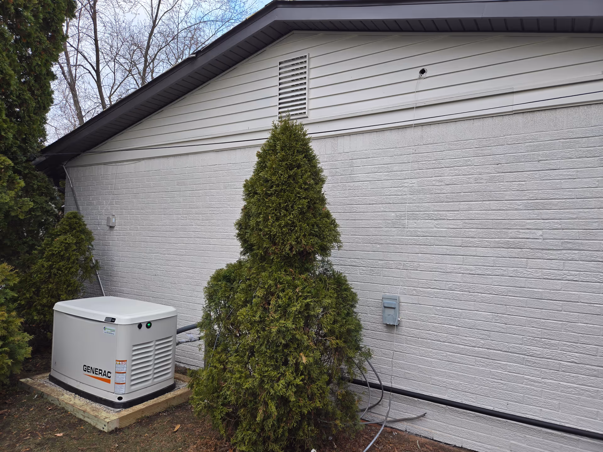 Exterior of Amor Novi Boutique Senior Living with air conditioner unit and shrubs along the wall.