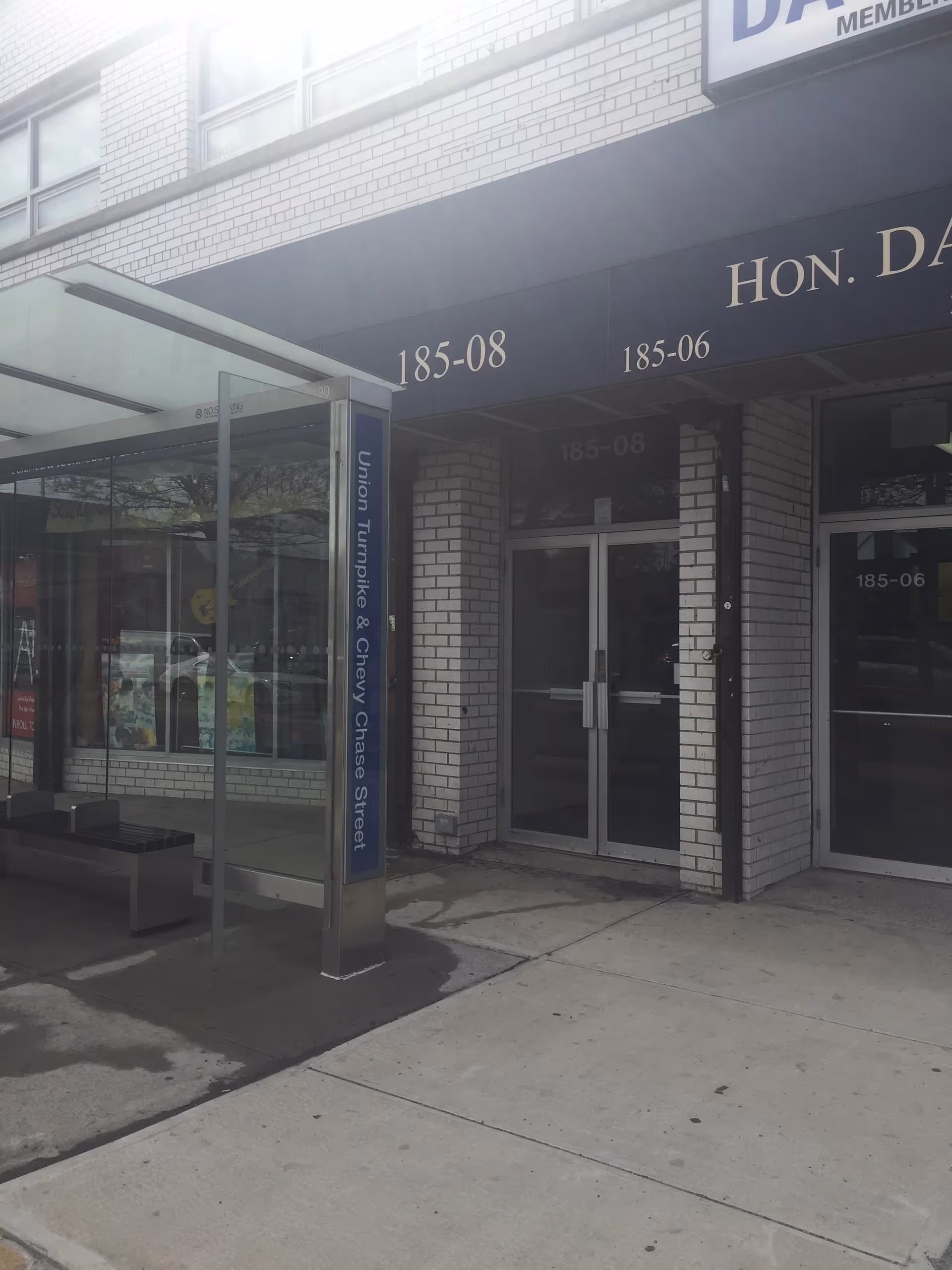 Exterior view of a senior facility entrance with glass doors and street signage.