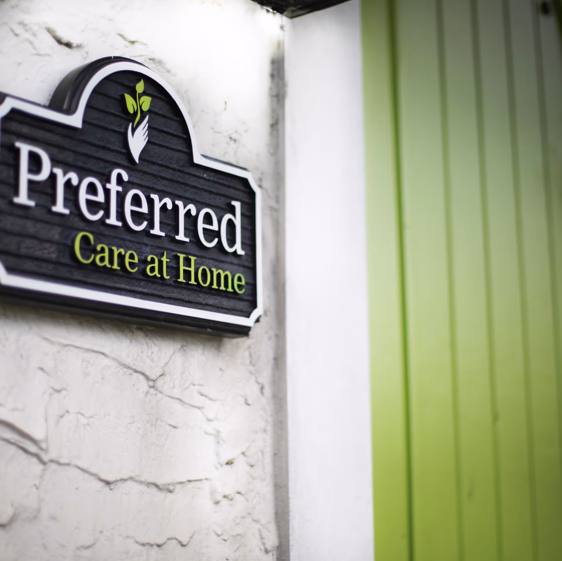 Exterior wall sign reading 'Preferred Care at Home' with green siding.