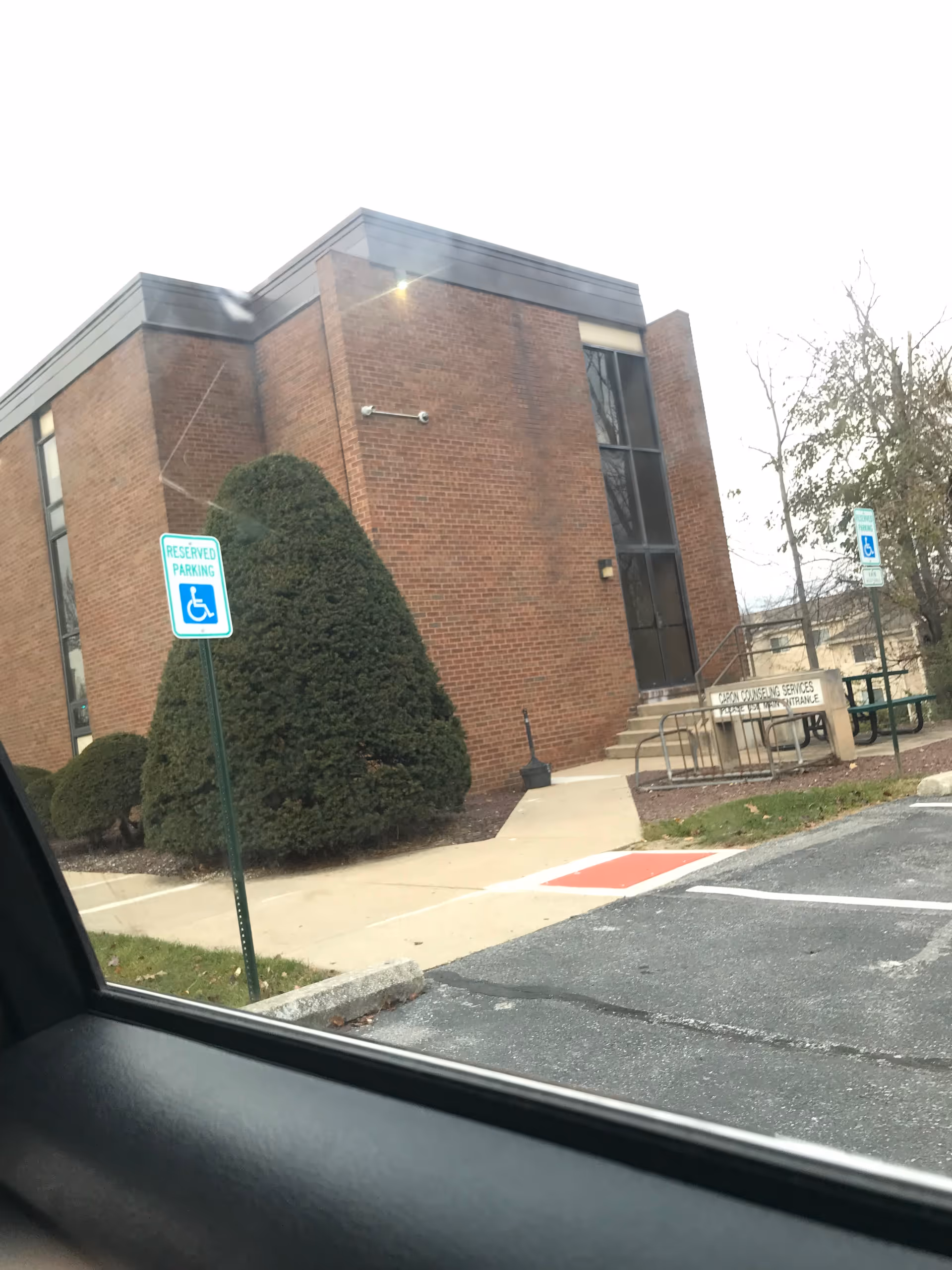 Brick building exterior with front entrance stairs and handicap parking signs.