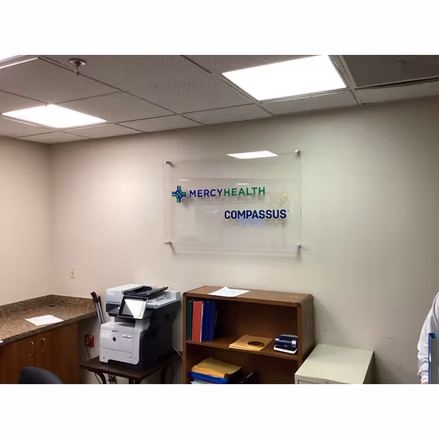 Office area with a printer, cabinets, and a Mercy Health Compassus sign on the wall.