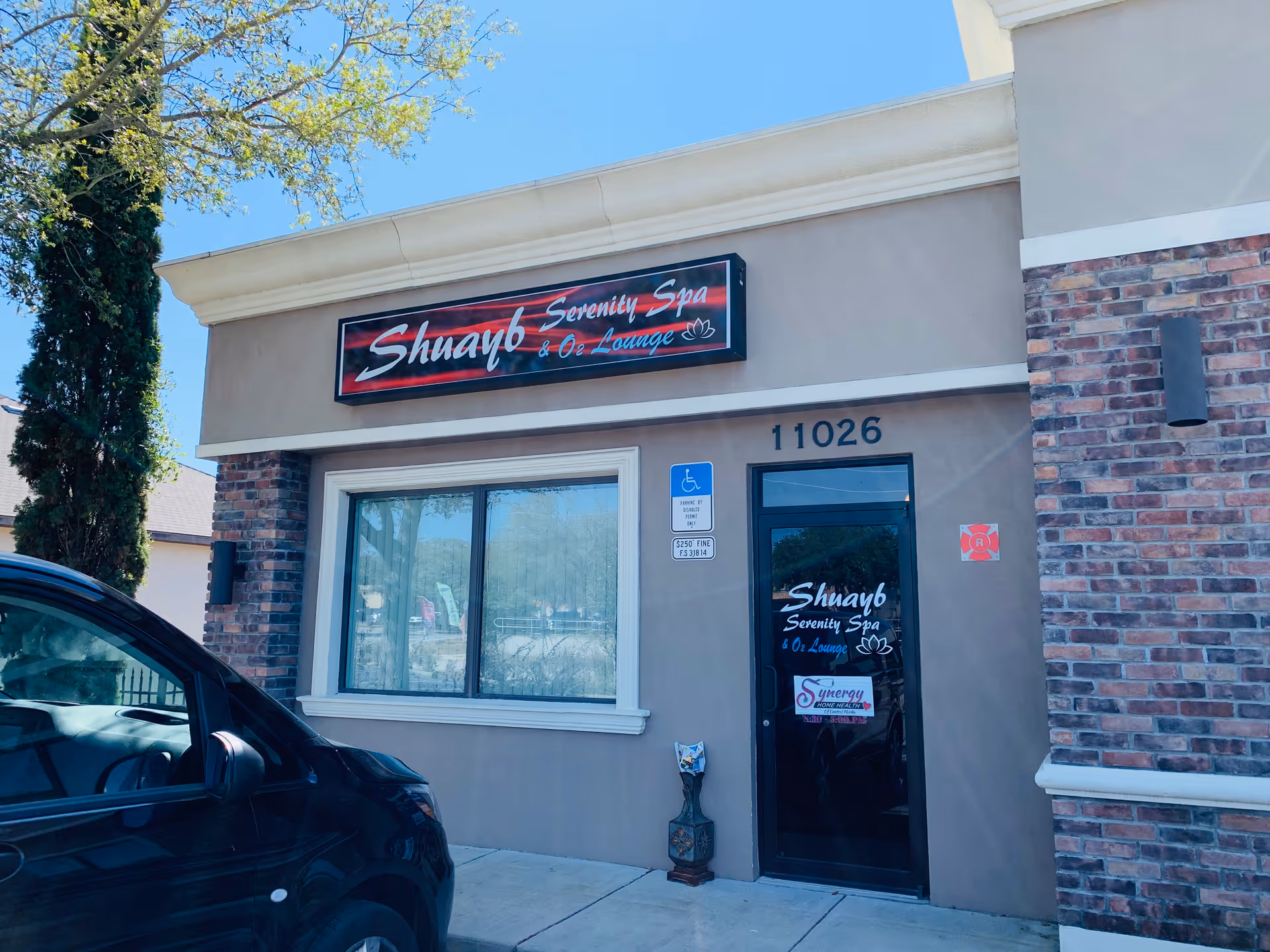 Exterior storefront with tan walls, brick accents, handicap sign, and glass door labeled 11026.