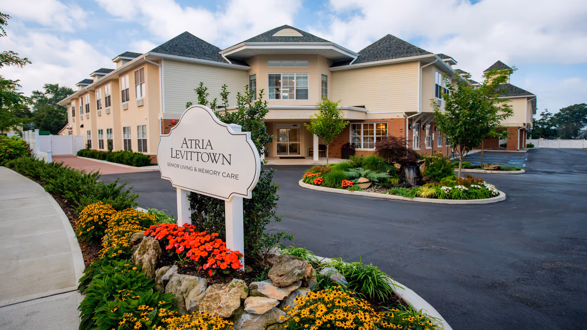 Exterior view of Atria Levittown senior living facility with landscaped entrance.
