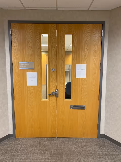 Double wooden doors with narrow windows in a hallway of a senior facility.