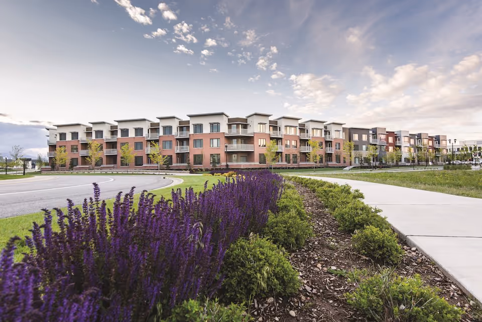 Front exterior view of Sagewood at Daybreak, with the building facade and landscaped flower beds.