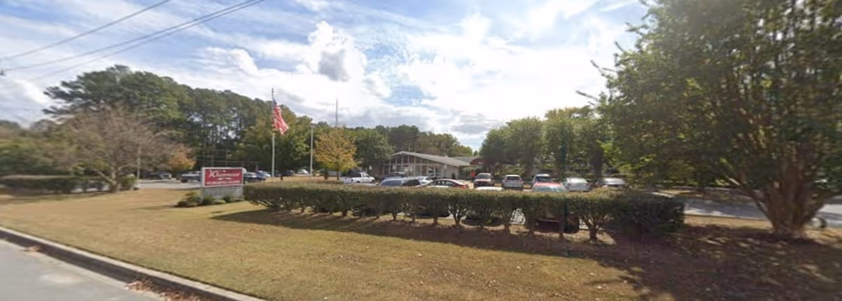 Exterior view of Wicomico Nursing Home showing parking lot, sign, trees, and shrubs