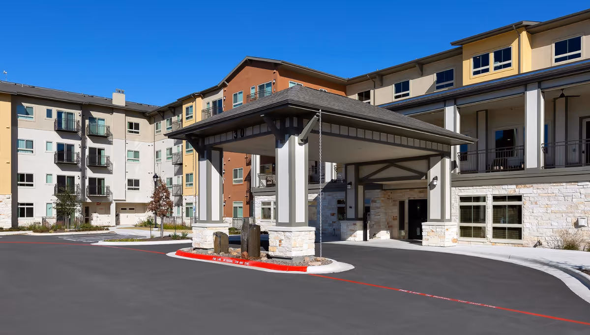 Exterior view of a multi-story senior living building with a covered entrance and driveway.