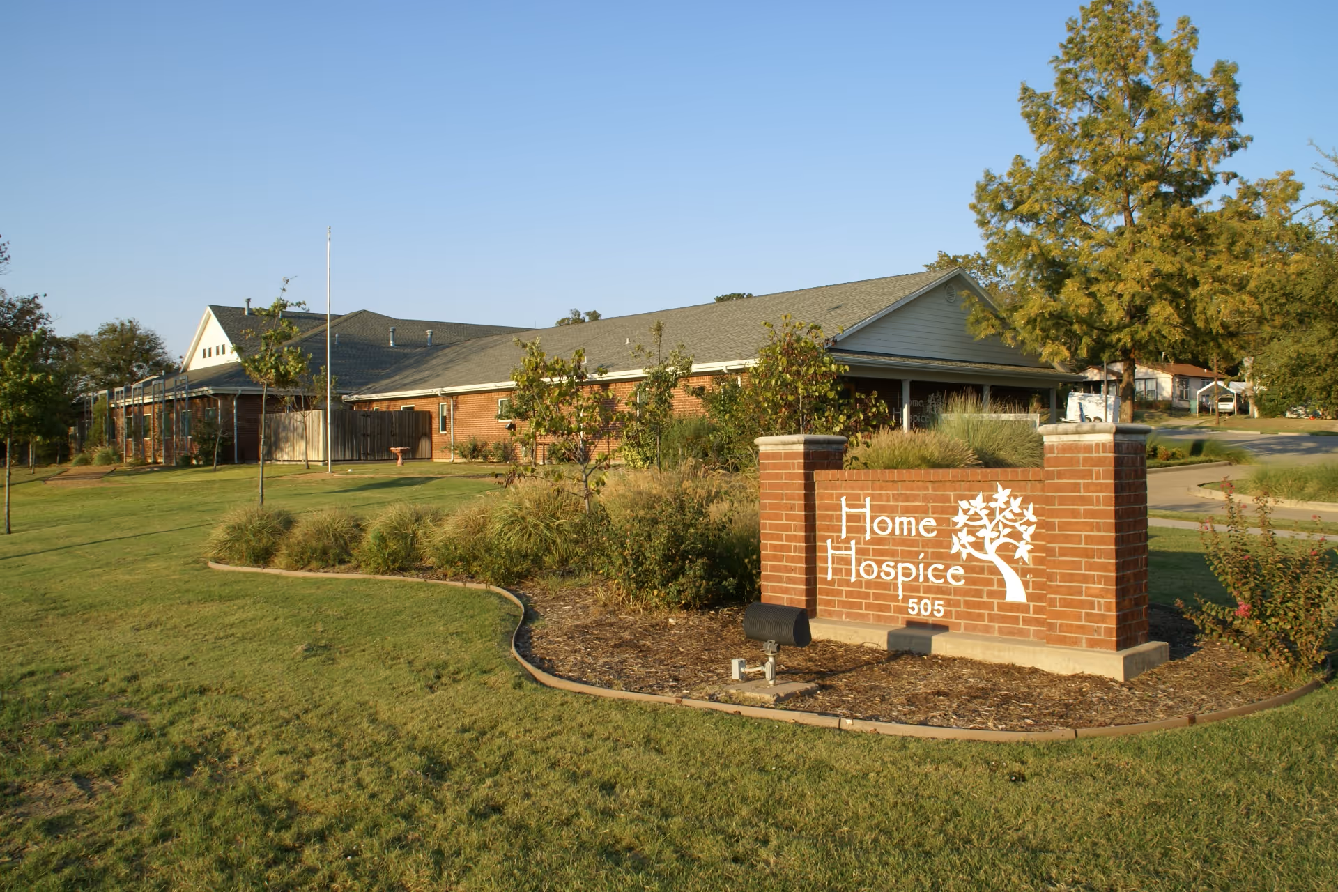 Exterior view of a single-story hospice building with a brick sign reading Home Hospice.