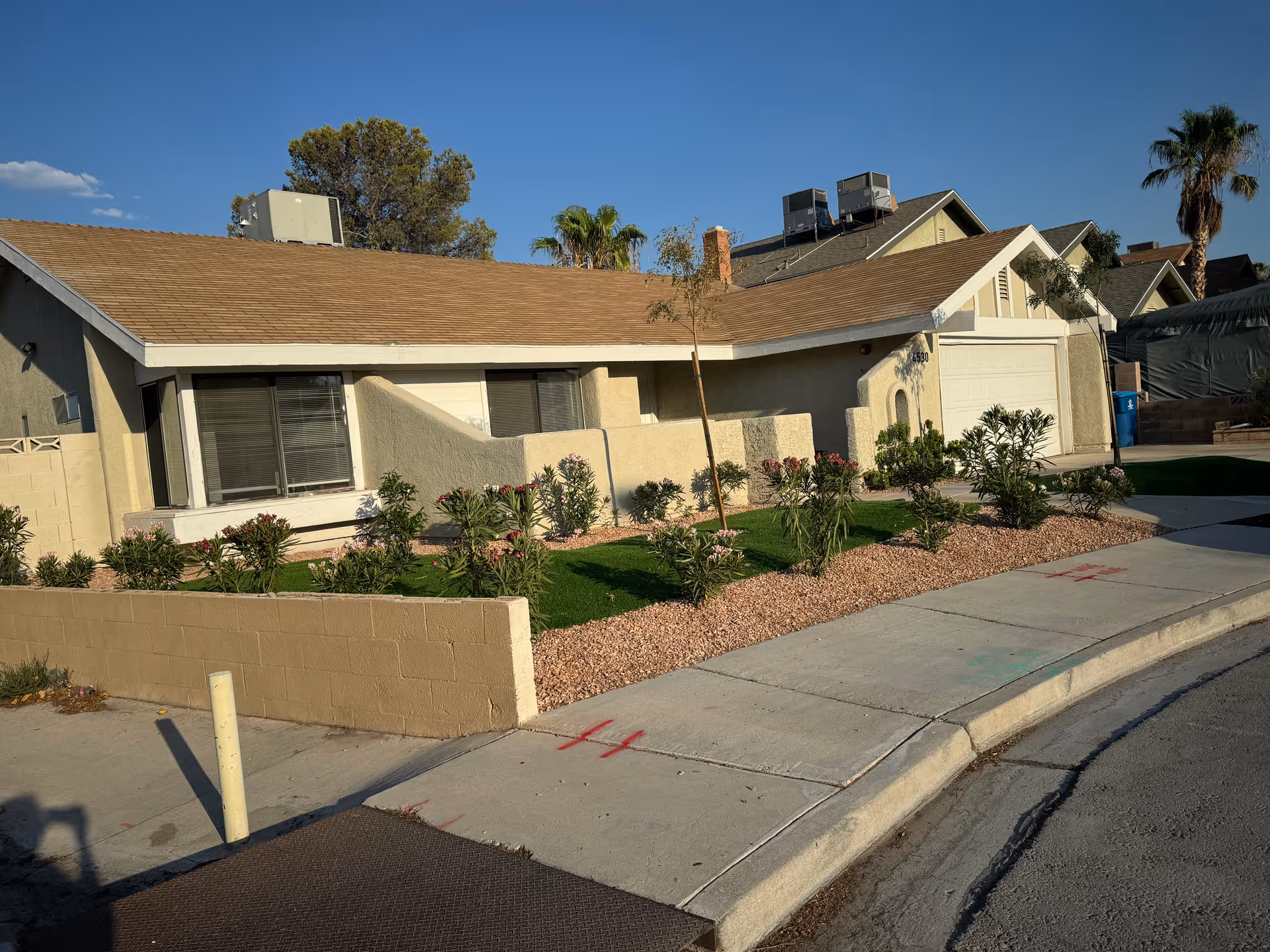 Beige single-story senior living facility with manicured front yard and sidewalk