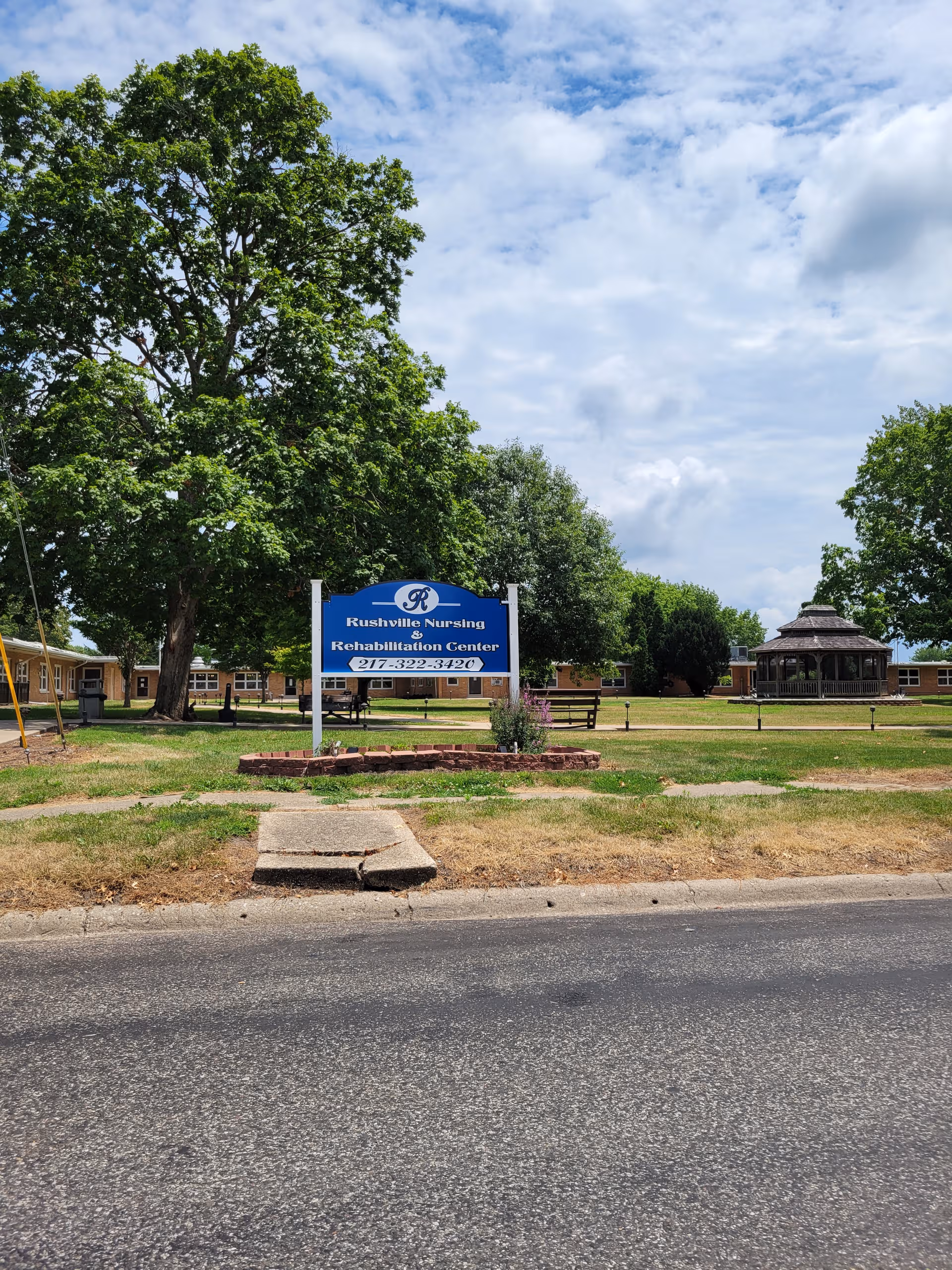 Rushville Nursing and Rehab Center exterior with sign, trees, and lawn.