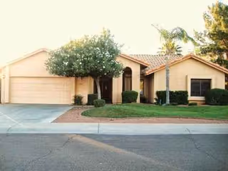 A single-story villa-style home with a landscaped front yard and driveway.