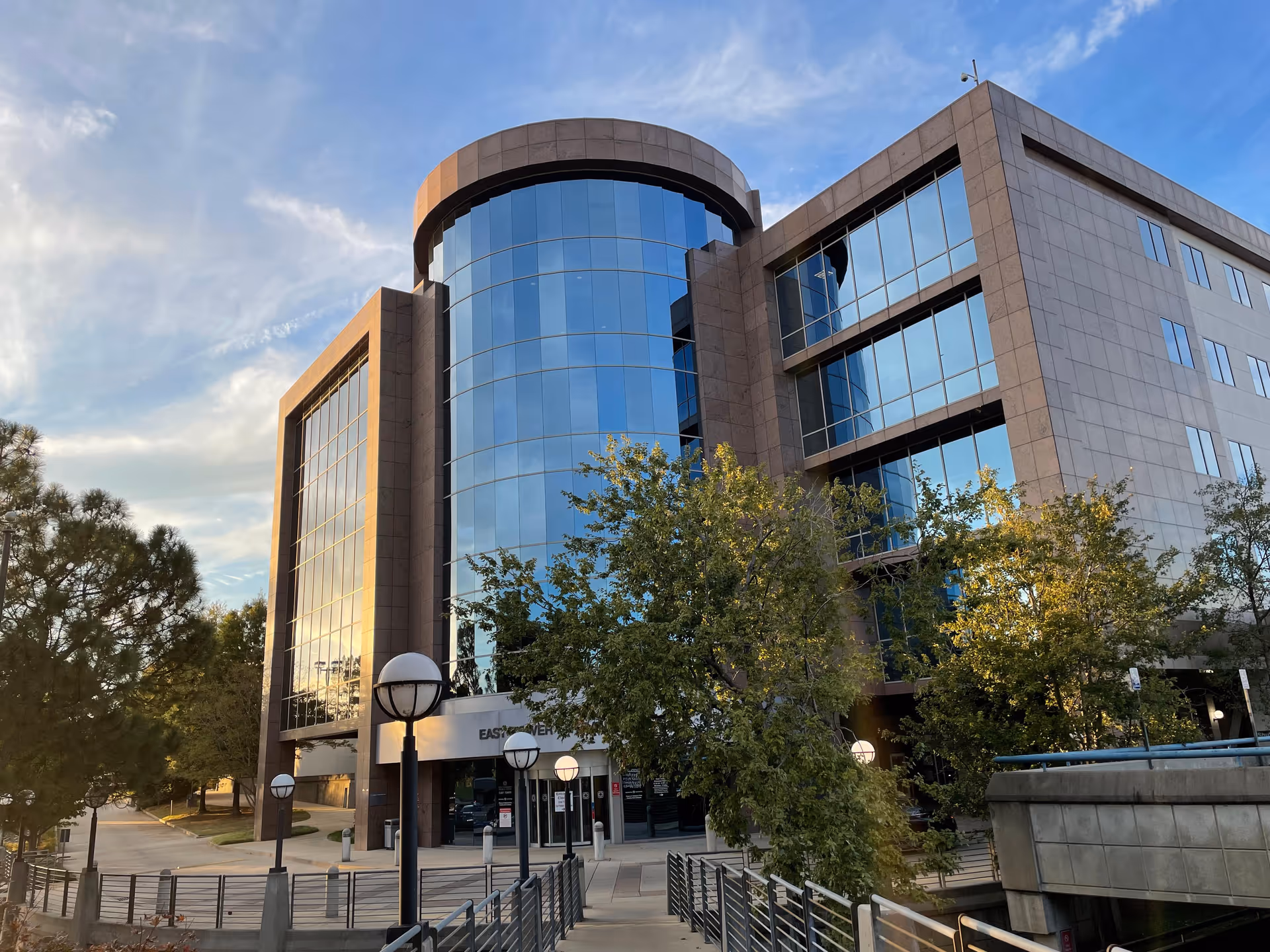 Sleek multi-story hospital exterior with curved glass entrance and surrounding trees.