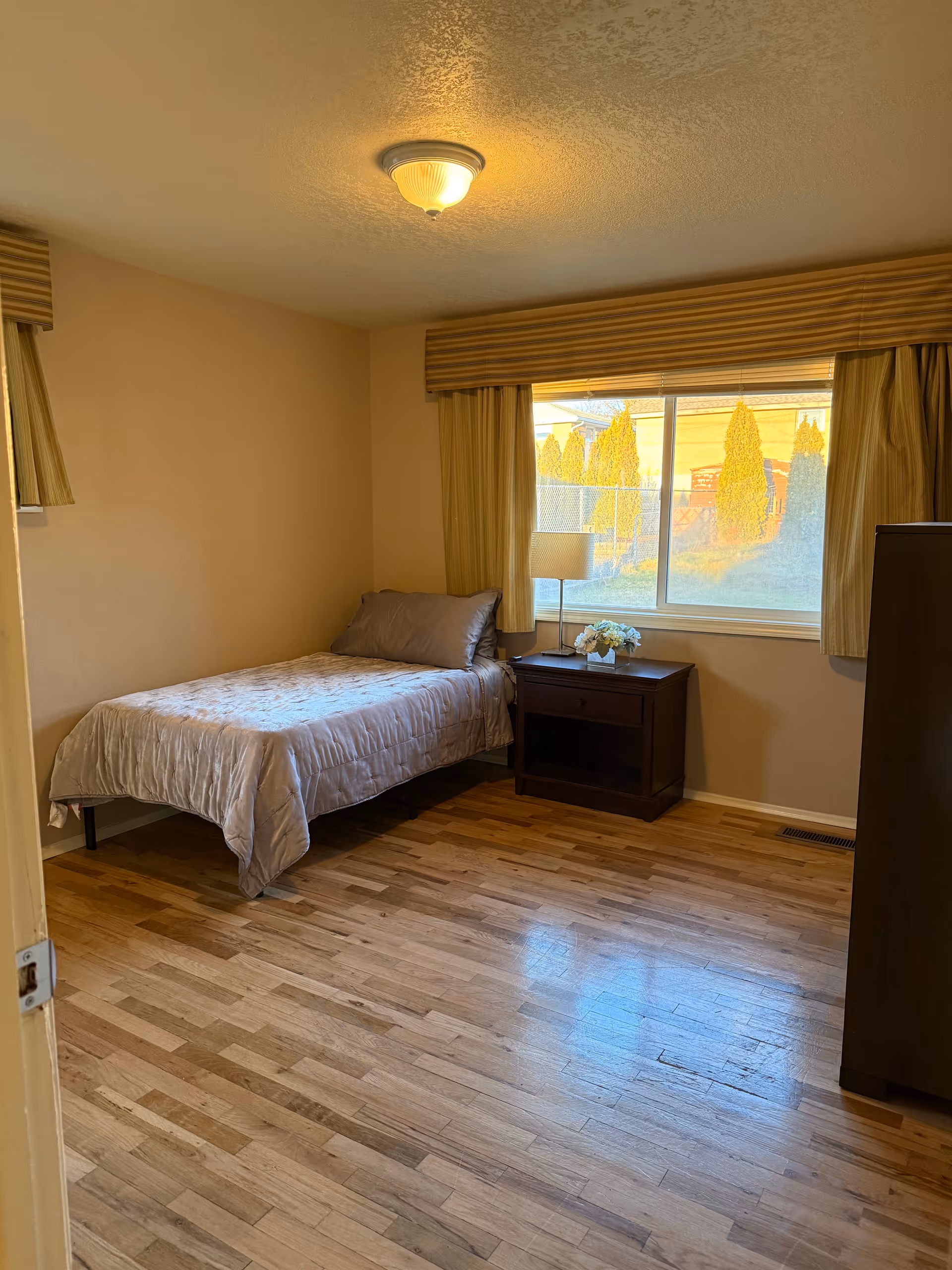 Bedroom with a single bed, nightstand, dresser, and a bright window