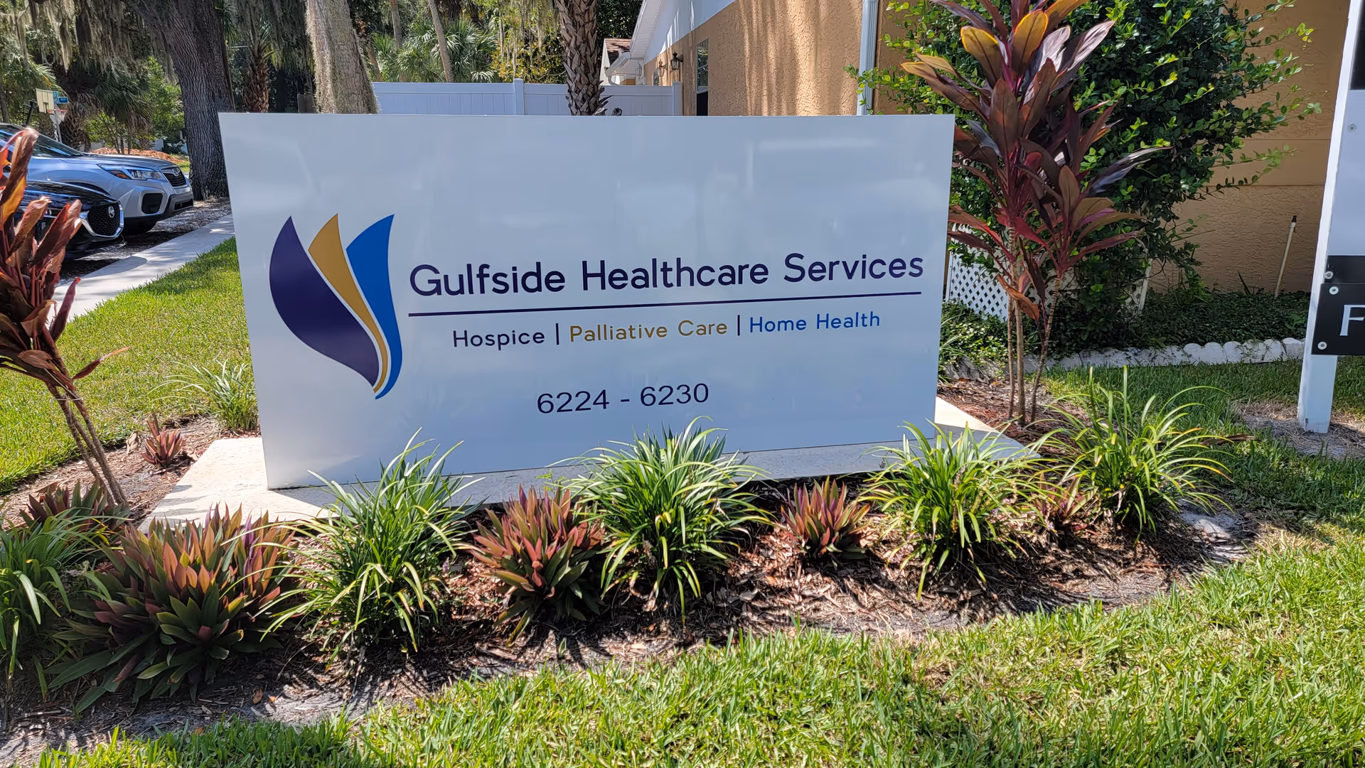 Outdoor sign for Gulfside Healthcare Services surrounded by plants near a building.