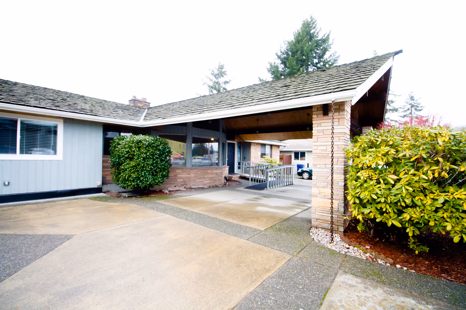 Exterior view of Olympic Adult Family Home and Hospice Care entrance with driveway and greenery.