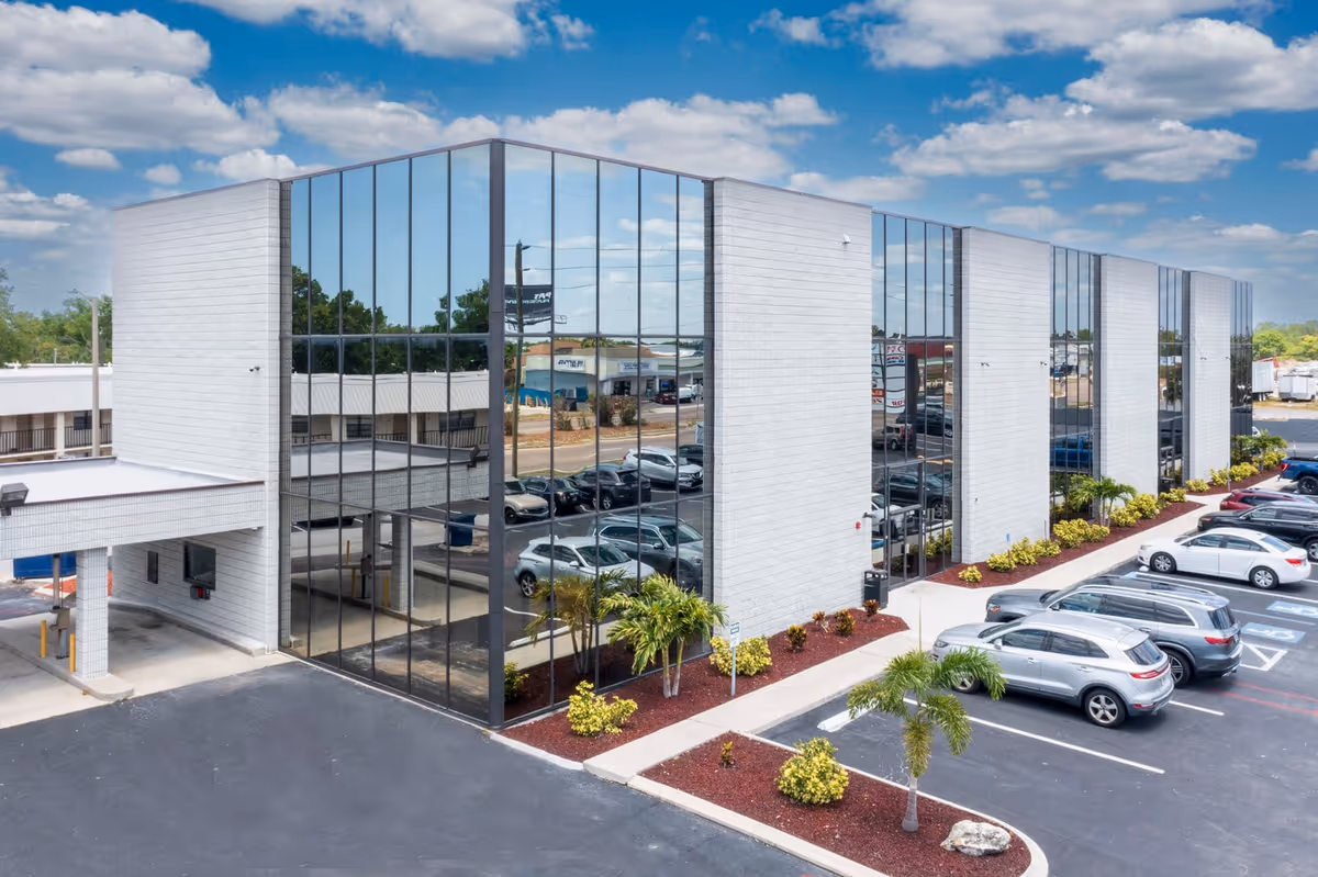 Exterior view of a modern glass-front senior living building with a parking lot.