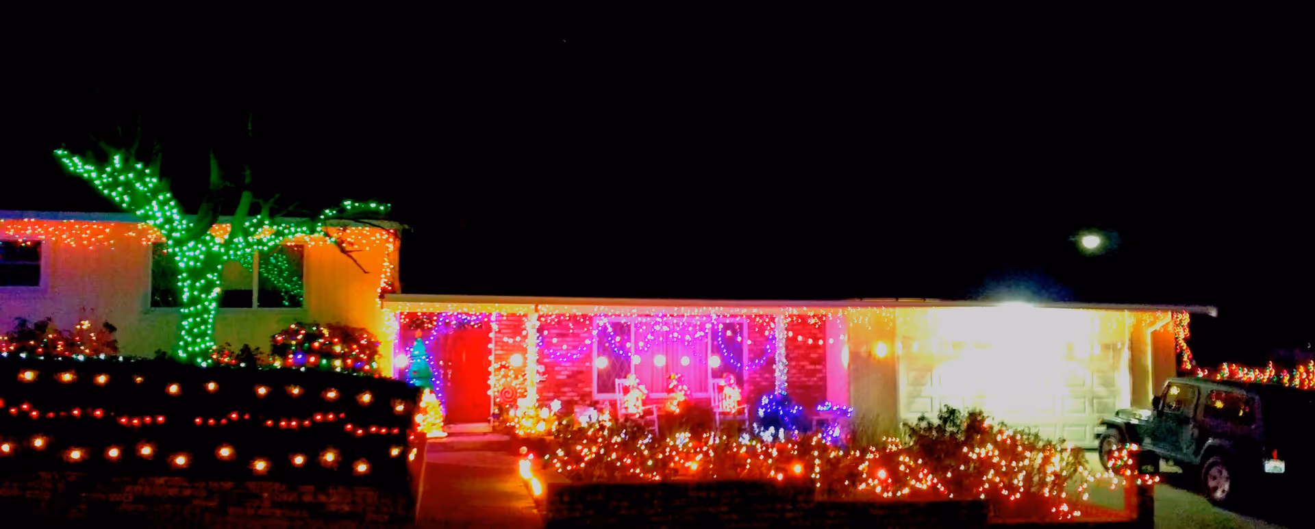 Night exterior view of The Sun Terrace House with colorful holiday lights and illuminated landscaping.